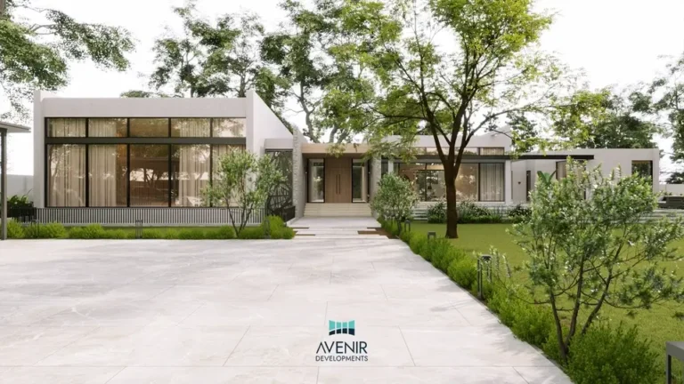 Single-storey modern farmhouse with large glazed openings behind a paved forecourt and trees